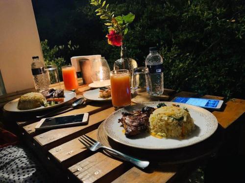 a wooden table topped with plates of food and orange juice at Moon Nest in Dhoāpālong