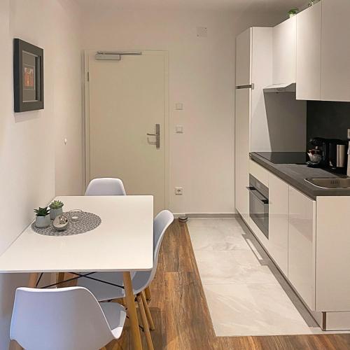 a white kitchen with a white table and chairs at Nurban Apartments Oldtown in Nürnberg