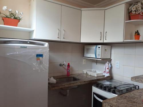 a kitchen with white cabinets and a sink and a microwave at Apto. 100m da feirinha da beira mar in Fortaleza