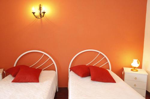 two beds with red pillows in a room at Casa capelinhos in Capelo