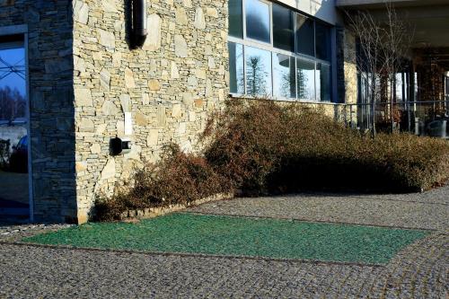 a brick building with a green grass next to a building at Aroma Stone Hotel Spa in Syców