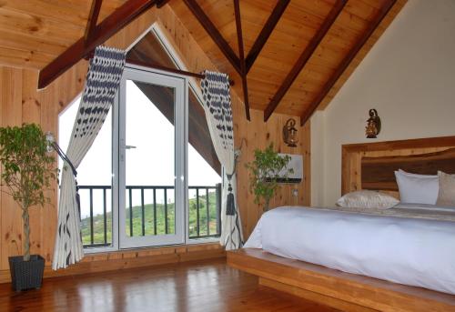 a bedroom with a large bed and a large window at Cottage San Francesco in Nuwara Eliya