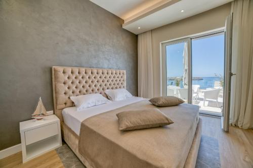 a bedroom with a large bed with a large window at Petra's Beachfront Penthouse in Sveti Stefan