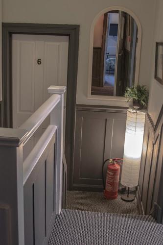 a hallway with a door and a lamp and a mirror at Abbey Court Guest House in Carlisle