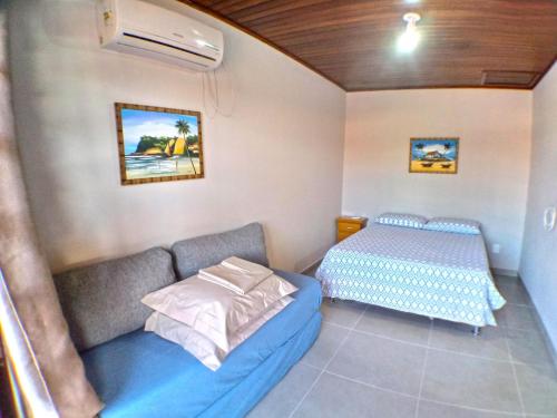una pequeña habitación con una cama y un sofá en Pousada Village Ubud, en Guarda do Embaú
