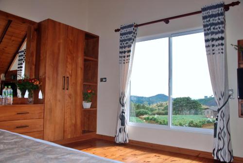 a bedroom with a bed and a large window at Cottage San Francesco in Nuwara Eliya