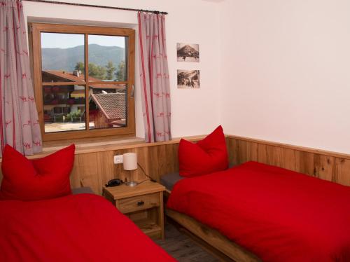 a bedroom with two red beds and a window at Haus im Moos - Chiemgau Karte in Inzell