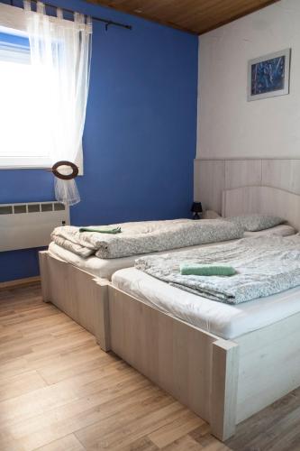 two beds in a bedroom with a blue wall at Pura Vida in Zaječí