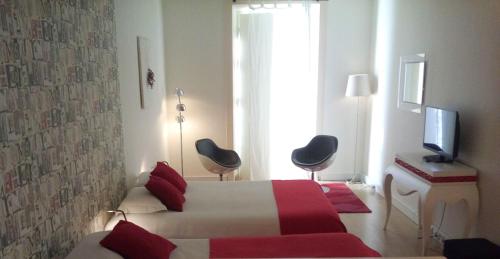 a bedroom with a bed and two chairs and a television at Evora Inn in Évora