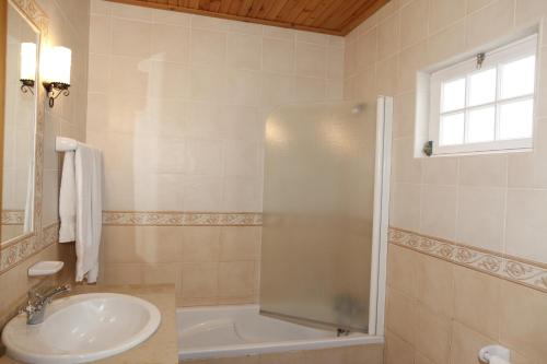 a white bathroom with a sink and a shower at Casa capelinhos in Capelo