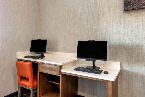 two computer monitors on a desk with a chair at Comfort Suites West Memphis I-40 I-55 in West Memphis