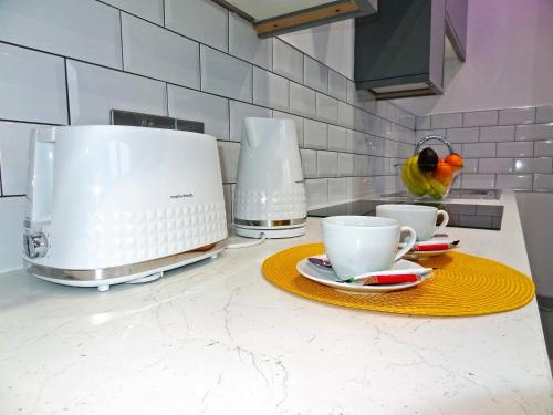 a bird standing on a kitchen counter with two coffee cups at Sea Nest Apartment by Seaside Llandudno in Llandudno