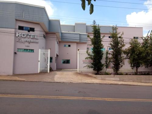 a white building with a fence in front of a street at Hotel ZM Premium in Cosmópolis