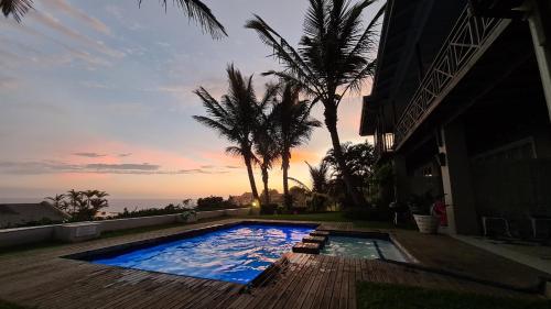 a swimming pool in front of a house with palm trees at Shaka's Seat Guesthouse-Check out our Pre-Easter Specials! in Ballito