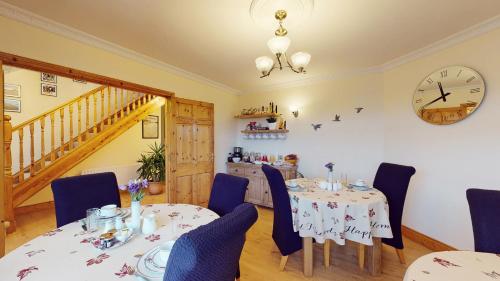 a dining room with two tables and a clock on the wall at Ross Beach Family Farmhouse B&B in Killala
