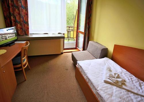 a room with a bed and a desk and a window at Hotel SOREA ĎUMBIER in Liptovský Ján
