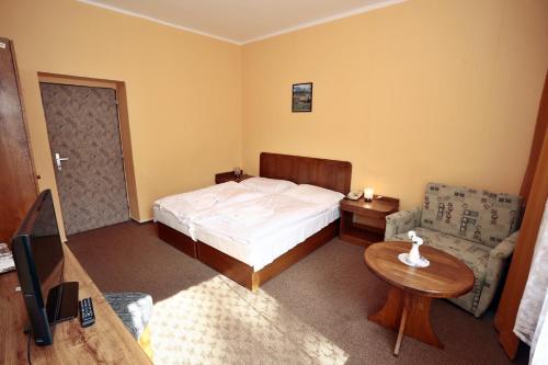 a bedroom with a bed and a table and a tv at Hotel SOREA ĎUMBIER in Liptovský Ján