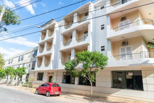 une voiture rouge garée devant un bâtiment blanc dans l'établissement VOA Hotel União, à Caxambu