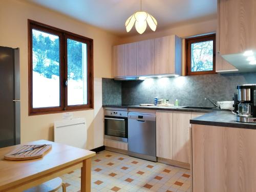 una cocina con armarios de madera y una mesa. en Chalet Roche Rousse, en Gresse-en-Vercors