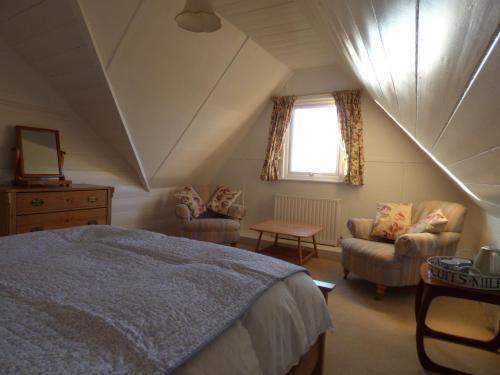 a bedroom with a bed and two chairs and a window at Trerhose B&B in Mullion