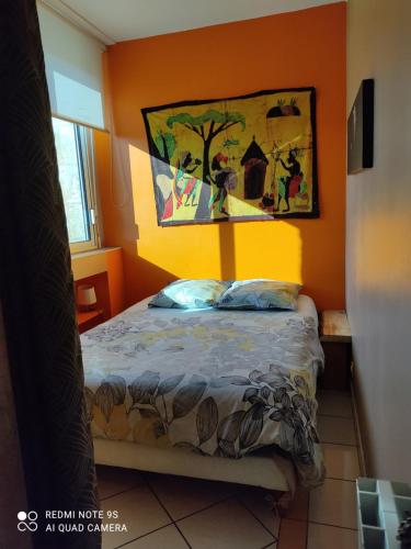 a bedroom with a bed with an orange wall at L entre cœur des deux mers in Cadillac