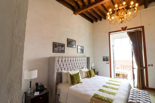 a bedroom with a bed and a chandelier at Quinta Alhóndiga Galindo Hotel Boutique in Cholula