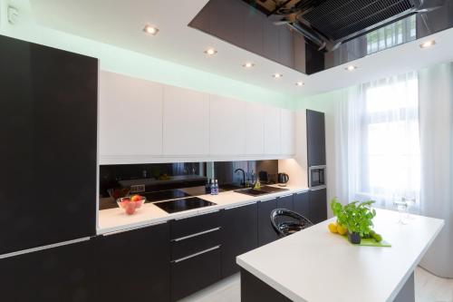 une cuisine avec des armoires noires et des comptoirs blancs dans l'établissement Prestige Apartamenty VINCI Centrum, à Kielce