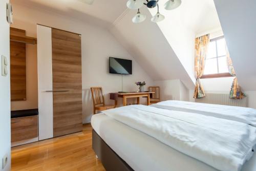 a bedroom with a large white bed and a desk at Weingut Burger in Kalladorf