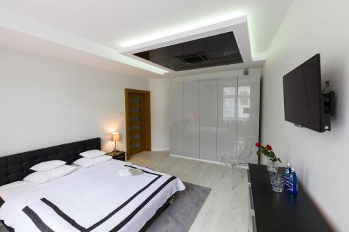 a white bedroom with a bed and a tv at Prestige Apartamenty VINCI Centrum in Kielce