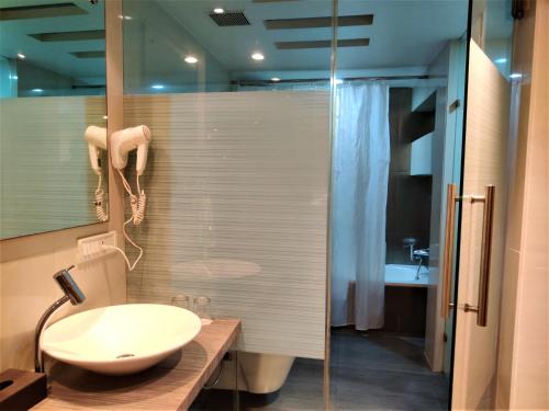uma casa de banho com um lavatório e uma cabina de duche em vidro. em Hotel Satkar Residency em Thane