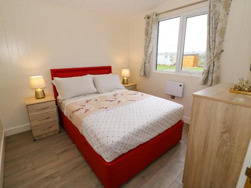 a bedroom with a red bed and a window at Cotswold View 2 in Evesham