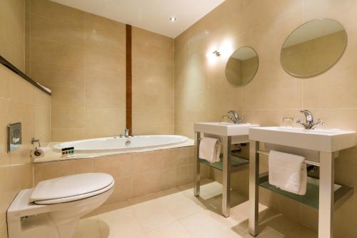 a bathroom with two sinks and a toilet and a tub at Athlone Springs Hotel in Athlone