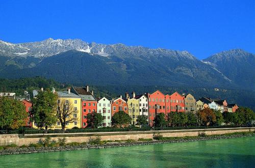 a group of buildings next to a river with mountains at Alp Art Hotel Götzens in Innsbruck