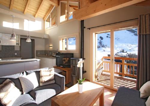 Il comprend un salon avec un canapé et une cuisine avec un balcon. dans l'établissement SUNWEB - Les Chalets Grizzly, à Les Deux Alpes