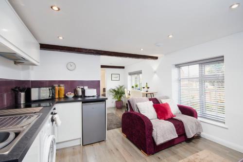 a kitchen and living room with a red couch in a room at Gateway Mews - Serviced Apartments in Kegworth