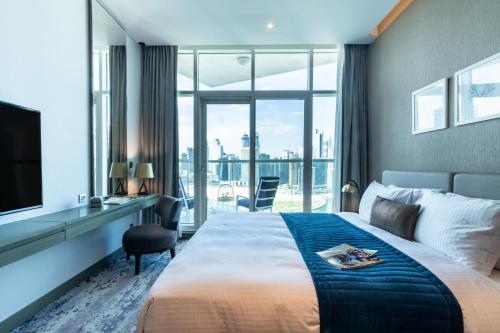 a hotel room with a bed and a desk and a television at The Smart Concierge - Damac Maison Prive in Dubai