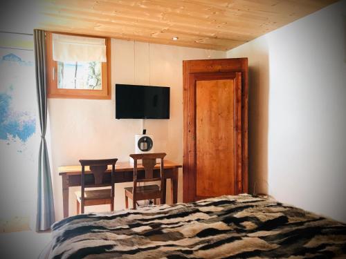 a bedroom with a bed and a desk and a television at Le 30 in Troistorrents