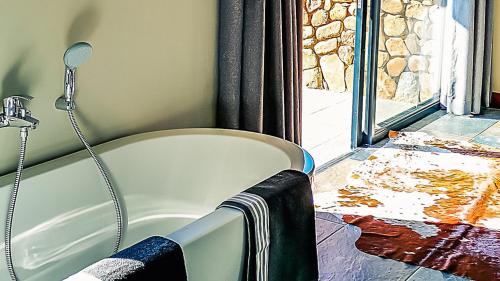 a bath tub sitting in a bathroom next to a window at Lodge @ Bankenkloof Private Game Reserve in Tierpoort