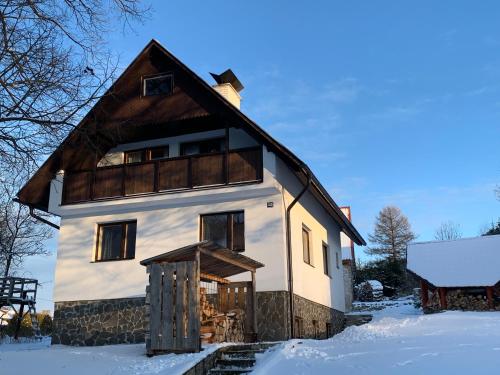 uma casa com um telhado de gambrel na neve em Chalupa Nad Lipou - Čičmany, turistika, sauna, krb em Cicmany