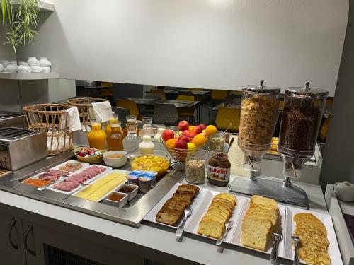 Un buffet con muchos tipos diferentes de comida en un mostrador. en HÔTEL LE CHAPON FIN, en Moissac