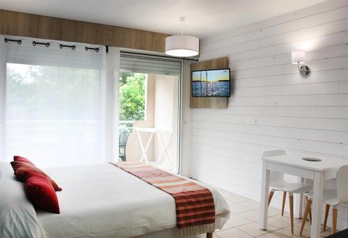 a bedroom with a bed and a table and a tv at Résidence du Parc Hossegor in Hossegor
