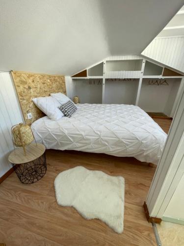 a bedroom with a bed with white sheets and a rug at Appartement idéalement situé Ax-les-thermes in Ax-les-Thermes