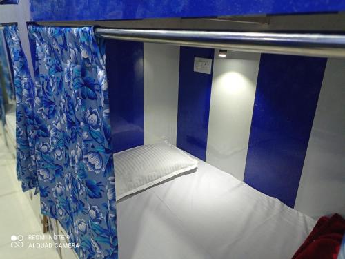 a small bed with a blue and white curtain at Kartar Yatri Niwas in Kānpur