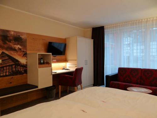 a hotel room with a bed and a desk and a couch at Höger's Hotel & Restaurant in Bad Essen