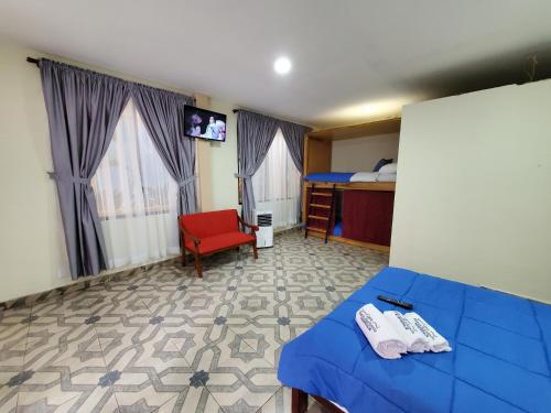a bedroom with a blue bed and a red chair at CASA BLANCA HORTENCIA in Sucúa