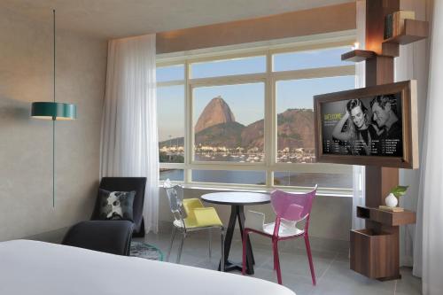 um quarto de hotel com uma mesa e cadeiras e uma janela em Yoo2 Rio de Janeiro by Intercity no Rio de Janeiro