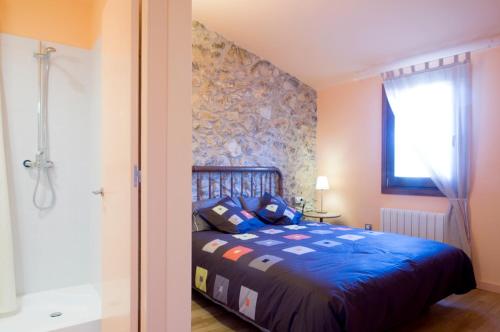 a bedroom with a blue bed and a shower at Ca l'Helena in Castellet