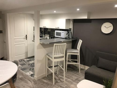 une petite cuisine avec deux chaises et un comptoir avec une horloge dans l'établissement Jardin de la Béchade, à Bordeaux