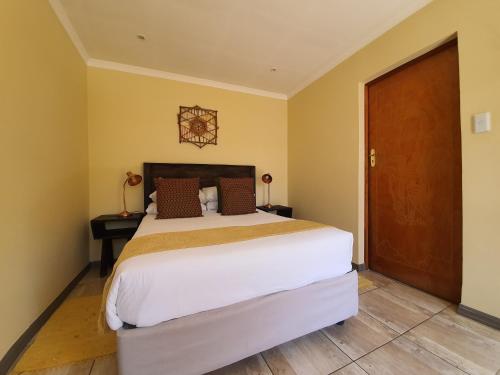 a bedroom with a large bed and a wooden door at Lebo's Soweto Backpackers in Soweto