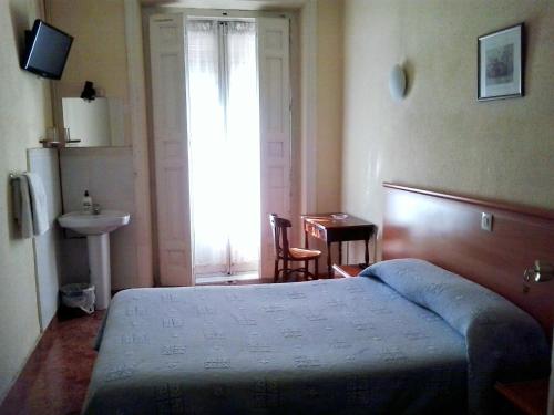a bedroom with a bed and a sink and a window at Hostal Alonso in Madrid